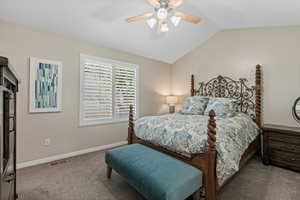 Carpeted bedroom with ceiling fan and vaulted ceiling