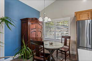 Dining space featuring a notable chandelier and high vaulted ceiling