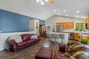 Living room featuring ceiling fan with notable chandelier, high vaulted ceiling, and dark wood-type flooring