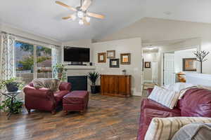 Living room featuring ceiling fan, lofted ceiling, and dark wood-type flooring