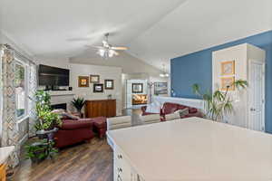 Kitchen with ceiling fan with notable chandelier, lofted ceiling, dark wood-type flooring, and white cabinets