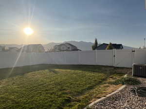 Yard at dusk featuring central AC unit and a mountain view