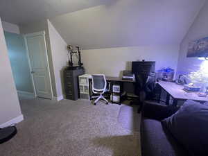 Home office with lofted ceiling and carpet floors