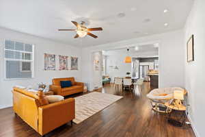 Living room featuring a healthy amount of sunlight, ceiling fan, and dark hardwood / wood-style floors