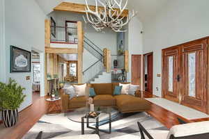 Living room with high vaulted ceiling, hardwood / wood-style flooring, and an inviting chandelier