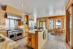 Kitchen with built in appliances, a textured ceiling, and light brown cabinets