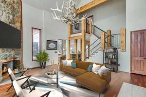 Living room featuring a high ceiling, a stone fireplace, beamed ceiling, a chandelier, and dark hardwood / wood-style flooring