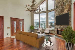 Living room with a stone fireplace, hardwood / wood-style flooring, and a towering ceiling