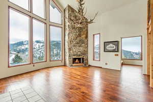 Unfurnished living room with a high ceiling, a mountain view, a stone fireplace, and light wood-type flooring