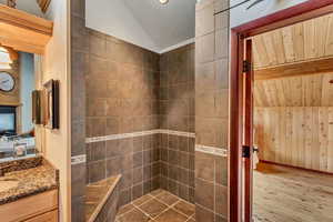 Bathroom with vanity, hardwood / wood-style flooring, lofted ceiling, and wooden walls