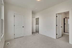 Unfurnished bedroom with visible vents, light carpet, and baseboards