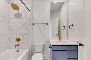 Full bathroom with vanity, tiled shower / bath combo, and toilet