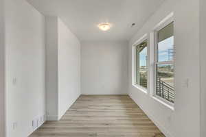Empty room with visible vents, baseboards, and light wood-type flooring