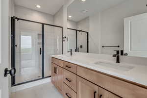 Full bath featuring double vanity, recessed lighting, a stall shower, and a sink