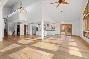 Unfurnished living room with ceiling fan, light wood-type flooring, and high vaulted ceiling