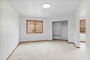 Unfurnished bedroom with light colored carpet and a closet