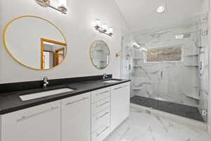 Bathroom with walk in shower, vanity, and lofted ceiling