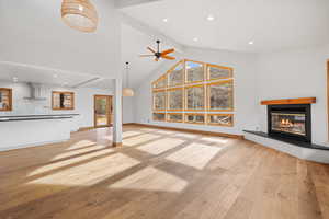 Unfurnished living room featuring ceiling fan, beam ceiling, light hardwood / wood-style floors, and high vaulted ceiling