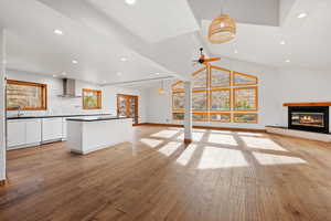 Unfurnished living room with ceiling fan, vaulted ceiling with beams, sink, and light hardwood / wood-style flooring