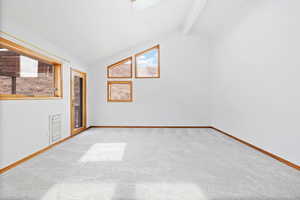 Unfurnished room featuring vaulted ceiling with skylight and light carpet