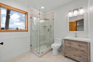 Bathroom with a shower with shower door, vanity, and toilet