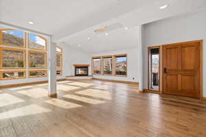 Unfurnished living room with beamed ceiling, light wood-type flooring, and a textured ceiling