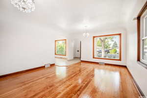 Spare room with light hardwood / wood-style floors, a healthy amount of sunlight, and an inviting chandelier