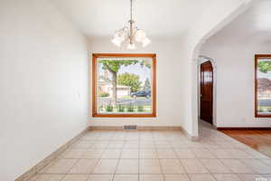 Empty room with light hardwood / wood-style floors and an inviting chandelier