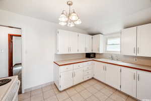 Kitchen featuring lofted ceiling, sink, pendant lighting, and white cabinets