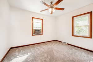 Carpeted spare room featuring cooling unit and ceiling fan