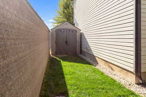 View of property exterior with a lawn and a storage unit