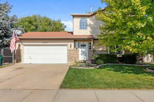 View of property with a garage and a front lawn