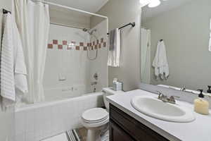 Full bathroom featuring vanity, toilet, and shower / bathtub combination with curtain