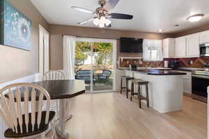 Kitchen featuring light hardwood / wood-style flooring, a kitchen breakfast bar, sink, stainless steel appliances, and white cabinetry