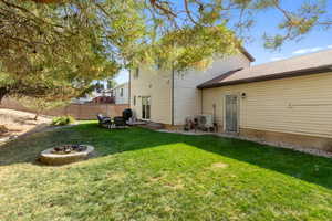 Back of property featuring an outdoor fire pit, a lawn, and ac unit