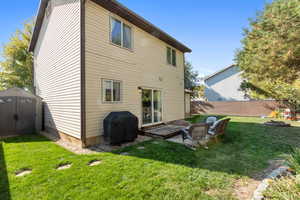 Rear view of house with a shed, a patio, and a lawn