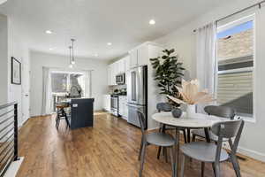 Kitchen with hanging light fixtures, a kitchen island, a breakfast bar area, white cabinetry, and stainless steel appliances