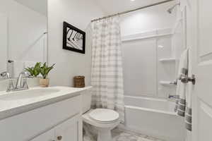 Full bathroom with vanity, shower / tub combo with curtain, and toilet