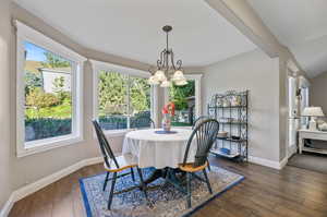 Dining room with a healthy amount of sunlight, a chandelier, and dark hardwood / wood-style flooring