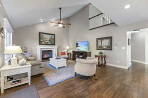 Living room with ceiling fan, laminate/wood-style floors, and high vaulted ceiling