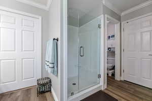 Bathroom with solid surface / wood-style floors, toilet, and an enclosed shower