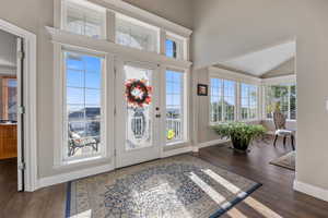 Entryway featuring laminate/wood-style floors, vaulted ceiling, and a healthy amount of sunlight