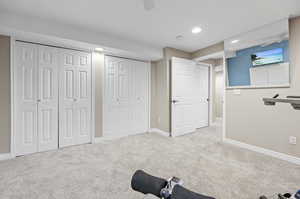 Bedroom featuring light colored carpet, multiple closets, and ceiling fan