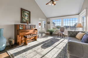 Living room featuring ceiling fan laminate/wood-style floors, and high vaulted ceiling