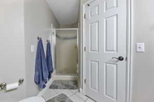 Bathroom featuring tile patterned flooring, a shower with door, a textured ceiling, and toilet