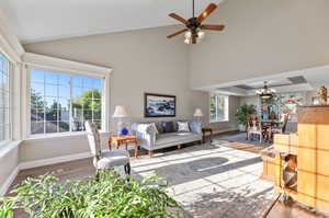 Living room featuring laminate/wood-style floors, ceiling fan with notable chandelier, and high vaulted ceiling