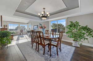 Dining space with a notable chandelier, a raised ceiling,  laminate/wood-style floors, a textured ceiling