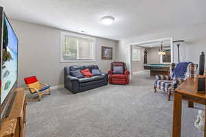 Carpeted living room with pool table and a textured ceiling