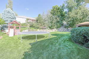 View of yard with a playground and a trampoline