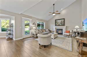 Living room with high vaulted ceiling, laminate/wood-style floors, and ceiling fan